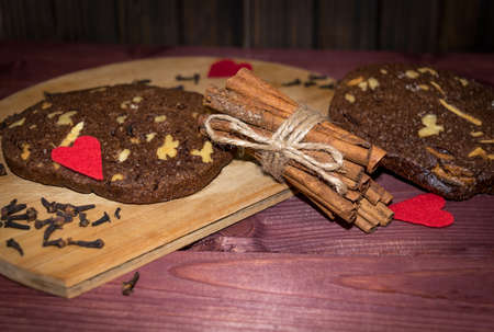 Walnut chocolate cookies with cinnamon sticks on wooden planks background toned selective focusの写真素材