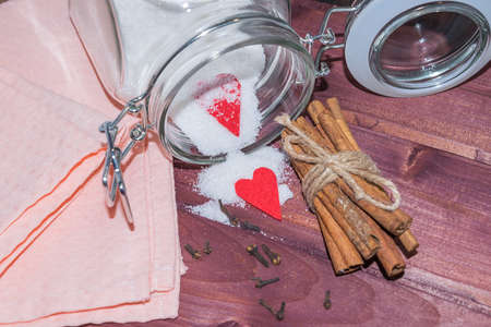Glass jar with sugar inside decorated with Valentine's heart and cinnamon sticks toned selective focusの写真素材
