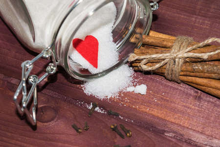 Glass jar with sugar inside decorated with Valentine's heart and cinnamon sticks toned selective focusの写真素材