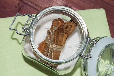 Glass jar with sugar and cinnamon sticks inside toned selective focus