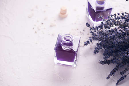 Lavender dried flowers on white with sea salt and essential oils in bottles. Space for text. Toned. Macro photo. Spa and relax concept.の写真素材