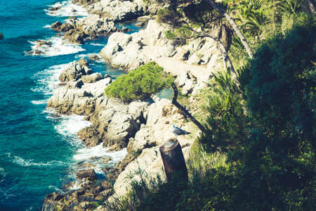 Sea view in Spain. Costa Brava holidays. Blue waves and rocks. Sandy beach.