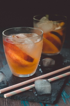 Peach aperol spritz with peach slices on wooden desk. Summer cocktails.の写真素材