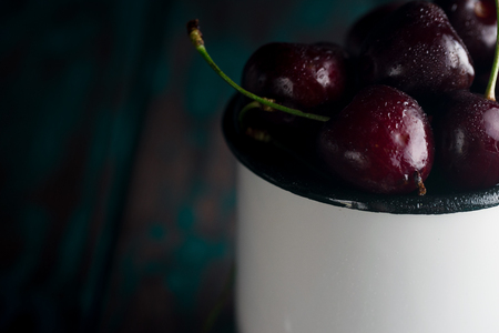 Cherries in tin cup on rustic wooden desk.の写真素材