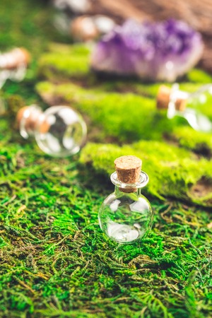 Magic flask and amethyst stone on emerald moss in the forest. Halloween theme.の写真素材
