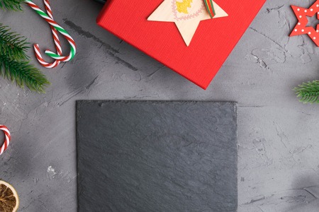 Fir branches on concrete gray background with red gift box. Space for text flat lay.の写真素材