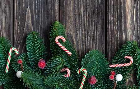 Christmas tree branches with cones. frozen berries and tiny candy canes. Rustic new year. Top view.