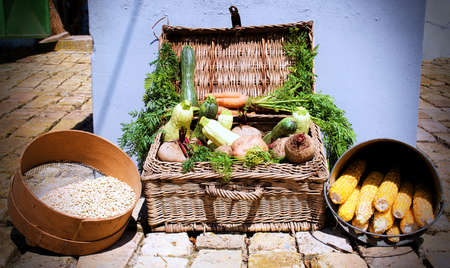 a basket full of various vegetables on the groundの写真素材