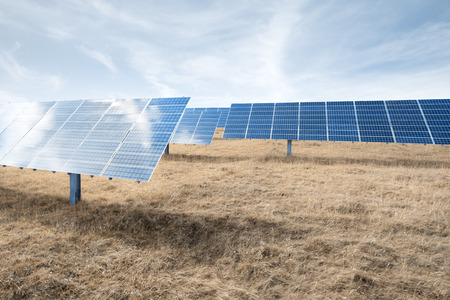 Solar cells installation on meadow against sky