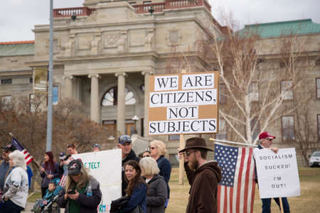 Helena, Montana - April 19, 2020: A protesting man holds a sign at a rally at the Capitol against the government shutdown. Wanting to reopen the economy because it's against constitutional rights.のeditorial素材