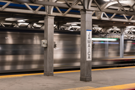 Long Island, NY - Circa 2017: Long exposure Jamaica railroad station terminal platform express train passing through busy mass transfer transit hubのeditorial素材