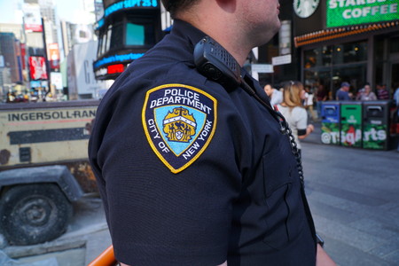 New York City - September 2016: NYPD officer stands guard in Times Square Manhattan patrol and survey public tourists looking for suspicious activity and safety threats. Police Department patch sleeve