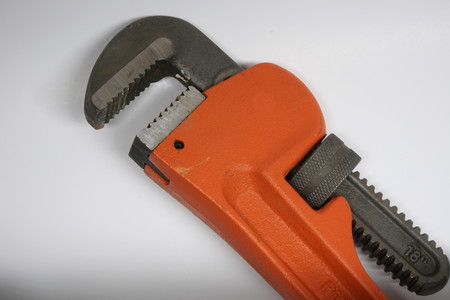 Isolated large plumbers pipe wrench on a white background. Used for home repair and construction for gas and water supply drain linesの写真素材