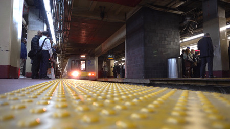 New York City, NY - May 4 2016: Long Island Railroad train arriving at the Penn Station platform below midtown as busy commuter businessmen wait to travel home out of Manhattan during rush hourのeditorial素材