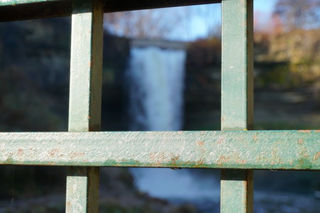 Beautiful winter waterfall photograph through steel fence - shallow depth of field focus. Minnehaha falls in Minneapolis Minnesotaの写真素材
