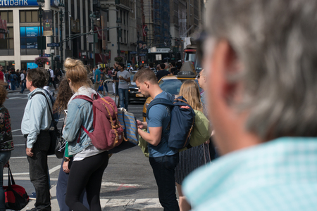 New York City, Circa 2017: Busy manhattan crosswalk intersection over the shoulder of man waiting to safely cross street during day timeのeditorial素材