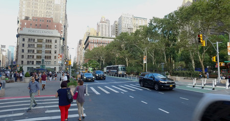 New York City, Circa 2017: Wide view outside NYC park of busy Manhattan intersection of cars passing...