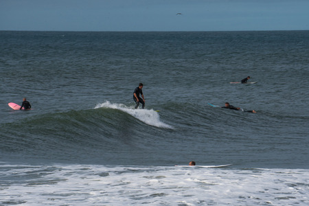 Outside view of surfers in the ocean riding waves during a summer day.