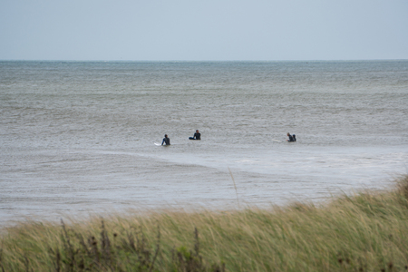 Montauk, NY - Circa 2017: Surfers wait in the ocean to catch and ride waves along the coast. Offshore hurricane sent large waves in Atlanticのeditorial素材