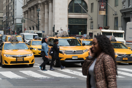New York City - Circa 2017: NYC yellow taxi cab stop at traffic light pedestrians cross street in...
