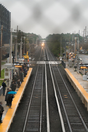 Long Island, NY - Circa 2017: Long Island Railroad train travel on track to station platform. People commute public transportation into Manhattan. Vertical Frameのeditorial素材