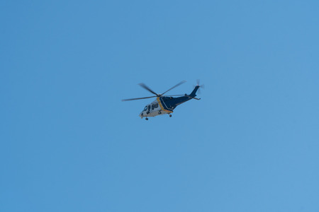 Generic blue and white police helicopter with visual camera surveillance equipment fly in sky high above city aerial patrolの写真素材