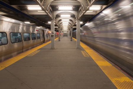 Long Exposure of high speed train passing station platform waiting departing train at railroad terminal hubの写真素材