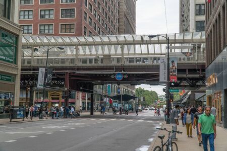 Chicago, Illinois, USA - Circa 2019: View of downtown street corner intersection during morning rush hour commute loop train passing on overhead track past buildingsの写真素材