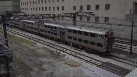 View of long distance transit passenger train passing through railroad track yard view from overhead during day time.の写真素材