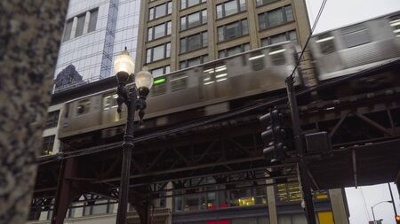 Chicago L train day time exterior establishing shot in front of downtown urban apartment buildings. Motion blur of train traveling in motionの写真素材
