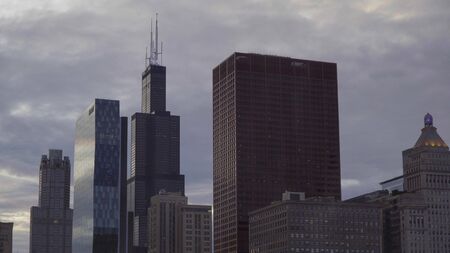 Day time exterior establishing shot stock photo of Downtown Chicago skyline in evening. Tall tower headquarter buildings rise high above cityscape apartment buildingsの写真素材