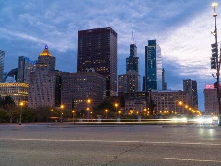 Chicago skyline looking past a busy downtown road at night with car traffic light trails passing through intersection long exposureの写真素材