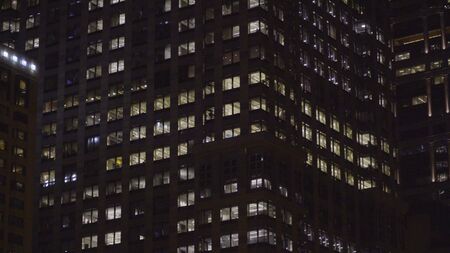 Generic night time establishing shot of typical apartment or office building in the dark. NX exterior of building with illuminated windows from insideの写真素材