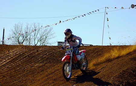 Dirt bike rider just landing jump in race.