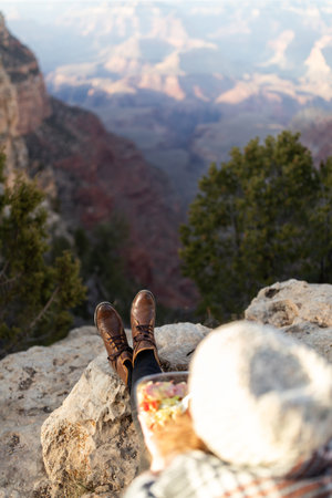 A man sitting on the edge of a cliff in the Grand Canyon National Park, Arizonaの写真素材