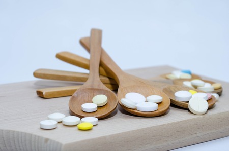 Pills and capsule with wooden spoon on wood backgroundの写真素材