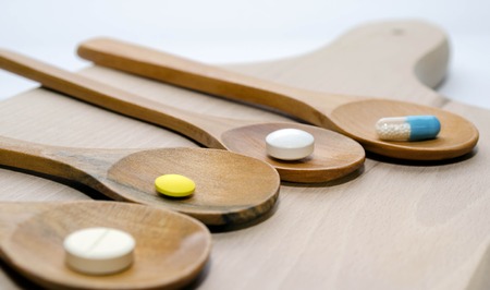 Pills and capsule with wooden spoon on wood backgroundの写真素材