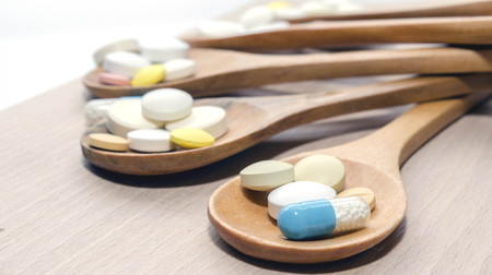 Pills and capsule with wooden spoon on wood backgroundの写真素材
