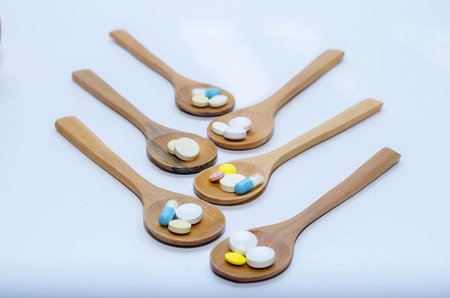 Pills and capsule with wooden spoon on wood backgroundの写真素材