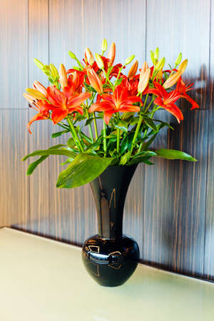 Bouquet of red lilly flowers in black vaseの写真素材