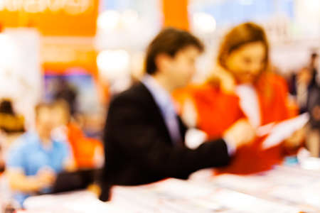 Man and woman sitting at the table watching tablet; blurred 100%の写真素材
