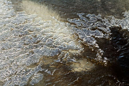 Thin ice layer of frozen creek waterの写真素材