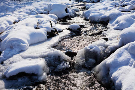 Closeup of a snowy small creek on wintertimeの写真素材