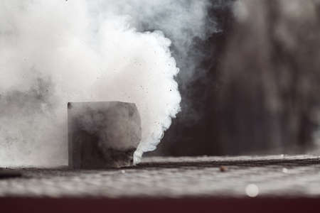 smoke coming from the chimney of the house in the winter, note shallow depth of field