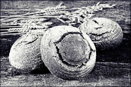 Decoration with a round rye bread and  dried branches of rye on a wooden boardの写真素材