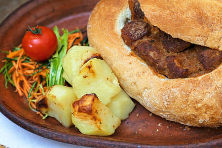 goulash in a bread on a clay plateの写真素材