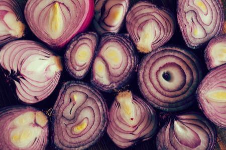 pieces of red onion on a wooden board, note shallow depth of fieldの写真素材