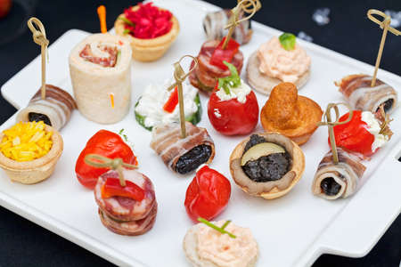 types of canapes for cocktails on a white plate, note shallow depth of field