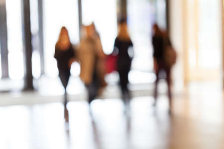 silhouettes of people as they move through the mal with light backgroundl, for the bluured backgroundの写真素材