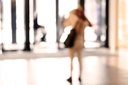 silhouettes of people as they move through the mal with light backgroundl, for the bluured backgroundの写真素材